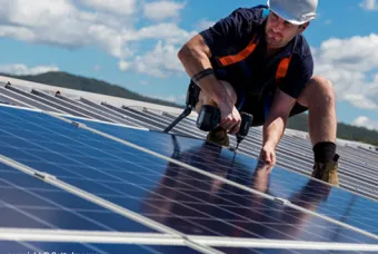 Un homme se tient sur le toit près de panneaux solaires